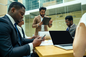 well-dressed business indian men making a report to subordinate employees in a modern office