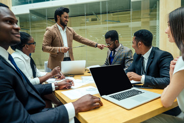 well-dressed business indian men making a report to subordinate employees in a modern office
