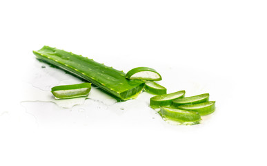 isolated on a white, sprinkled water background, a leaf of aloe, next to it slices with fresh aloe vera pulp