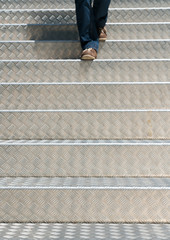 detail of a woman walking down aluminium stairs