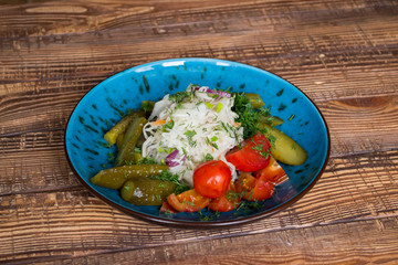 A bowl with pickles on a wooden background.