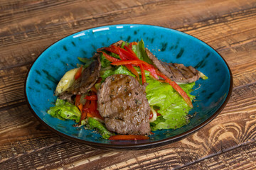 The salad with meat on the wooden table.