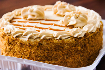 Board with delicious caramel cake on table