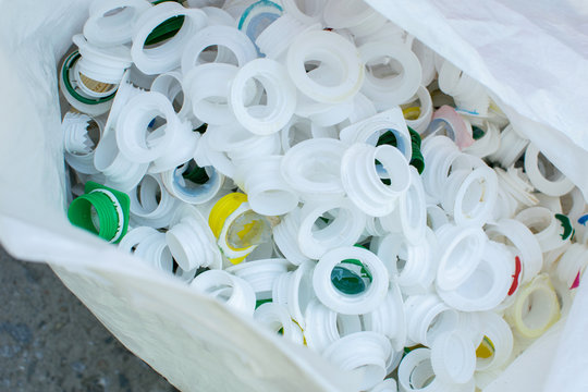 Recycling eco friedly concept background with colorful plastic bottle caps in cellophone package, environmental damage pollution