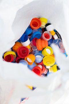Recycling eco friedly concept background with colorful plastic bottle caps in white cellophone package