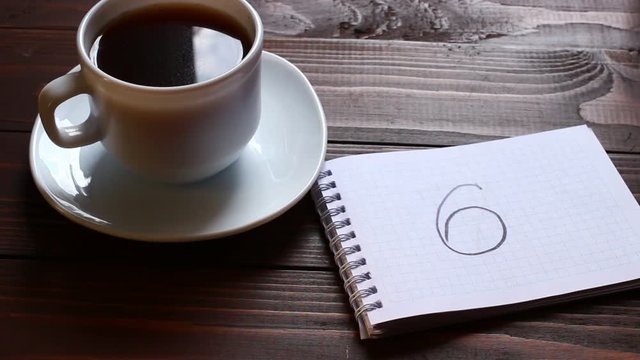 6 inscription and word in a notebook near a cup of coffee