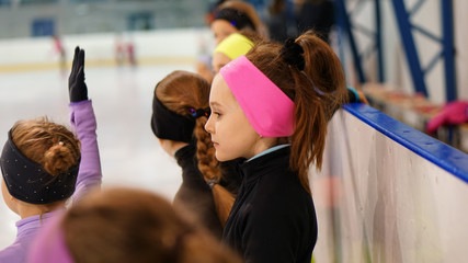 Fototapeta na wymiar Happy little girl in figure skating training at indoor rink