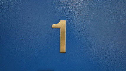 Metalic room number one on a wooden door