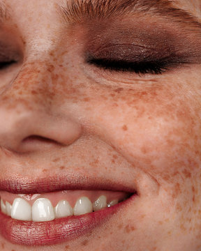 Closeup macro portrait of female face. Human woman half-face with day beauty makeup. Girl with perfect skin and freckles.