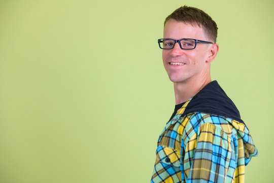 Closeup profile view of happy nerd man with eyeglasses smiling and looking at camera