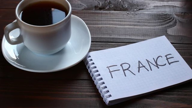 France inscription and word in a notebook near a cup of coffee