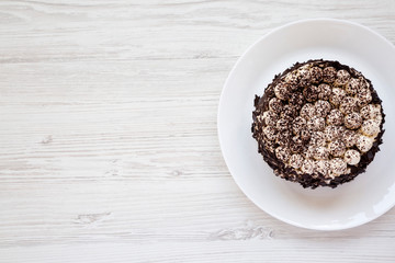 Homemade tiramisu cake on a white plate on a white wooden surface, top view. Flat lay, overhead, from above. Copy space.