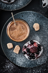 Coffee and chocolate cake with berries on a dark plate. Breakfast, coffee and dessert