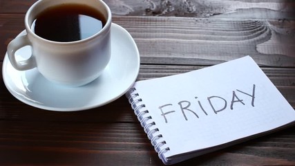 Friday inscription and word in a notebook near a cup of coffee