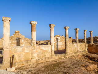 Ruins of an ancient temple, what is left are temple columns, Kato Paphos Archeological Park. Sandy color of the construction. Clear and blue sky.