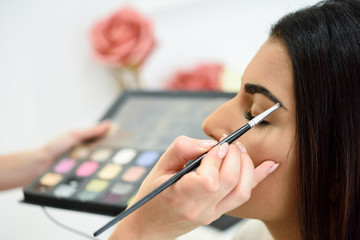 Makeup artist putting make-up on an woman's eyebrows - Powered by Adobe