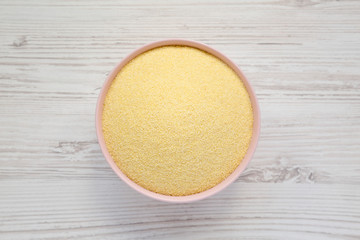 Dry semolina durum flour in a pink bowl over white wooden background, top view. Overhead, from above, flat lay.