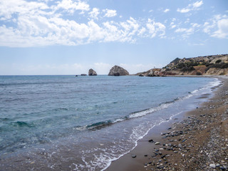 A rocky Aphrodite's beach in Petra tou Romiou, Cyprus. Beach stretches far away, surrounded by...