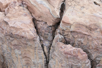 The rock is red with a fault in America. The crack in the stone, a piece of a broken stone is brown with stripes in white. Red stone with streaks of other colors.