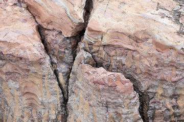 The rock is red with a rift. The crack in the stone, a piece of a broken stone brown color. Red stone with streaks of other colors. America canyon.