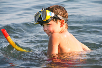 Little boy with a mask on his head prepearing to dive into the sea