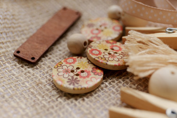Fototapeta na wymiar Close-up: Wooden buttons with floral print and other details for needlework lie on the burlap