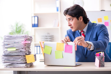 Young male handsome employee in conflicting priorities concept 