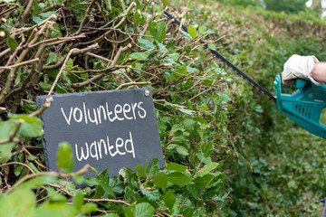 Volunteers needed for garden work. The sentence "volunteers needed" is written on a slate.