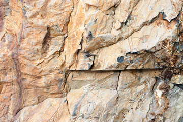 Natural stone relief, red color. Background rock with a gray texture with small cracks. Weathered stone layers of different colors.