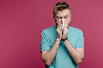 studio picture from a young man with handkerchief. Sick guy isolated has runny nose. man makes a...