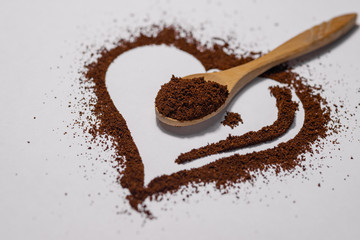 Ground coffee for espresso in shape of heart isolated on white background