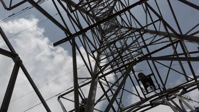 View below geometric pylon electricity distribution tower. Low perspective hazardous power network. Fast rotation.