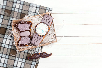 Fototapeta na wymiar Box of delicious creative cookies with copy space on checkered napkin on white wooden table. Happy Father's Day concept.