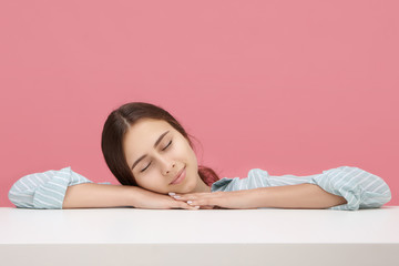 Sleepy student girl in striped blue shirt napping peacefully during class at university, pillowing face on her hands, keeping eyes closed. People, lifestyle, sleep, tiresome, learning and education