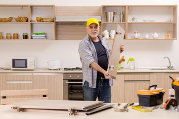 Aged contractor repairman working in the kitchen 