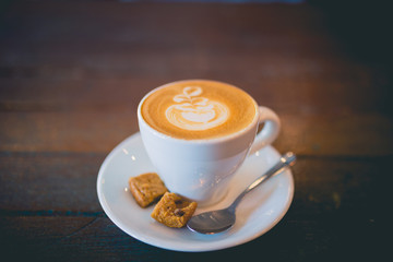Latte hot coffee with foam milk art on a wooden table