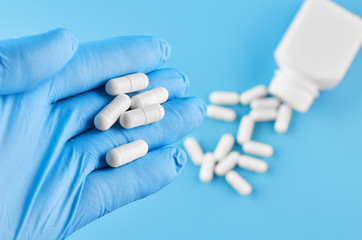 Young human hand hold pills tablets in palm. Healthcare, medical and pharmaceutical concept. Isolated on blue background.