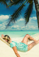 Woman sitting in hammock on the beach.