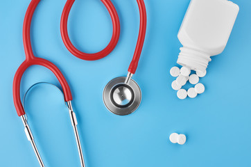 Pills tablets capsules closeup. On a blue background, a jar of medicine. On a blue background, a jar of medicine and a stethoscope.