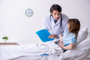 Fototapeta premium Male doctor visiting female patient in ward 