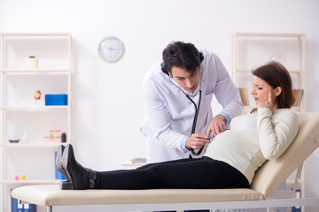 Fototapeta premium Old pregnant woman visiting young male doctor 