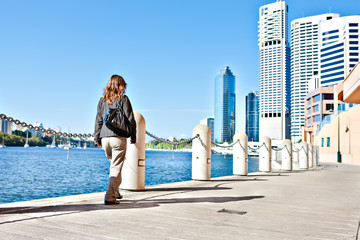 Lady walks on the street near to the river