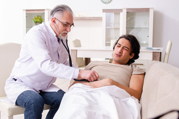 Obraz premium Old male doctor visiting young male patient 