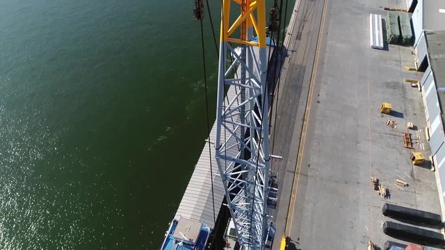 Aerial close up view of harbor crane camera moving down and panning up past boom also showing barge in background ready to leave dock located in Antwerp port in Belgium 4k high resolution quality