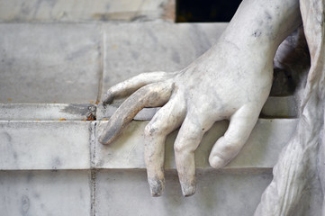 Partial view of a white sandstone sculpture whose hand was placed on a table. 