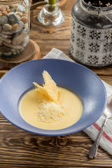 Homemade potato cream soup with grated cheese on wooden table