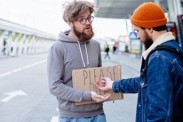 Fototapeta na wymiar Portrait of a cheerful beard man traveler hitchhiking holds cardboard with text 