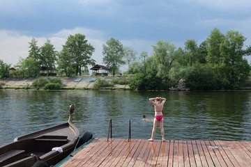 Fototapeta na wymiar little girl jumping from a pier by the river