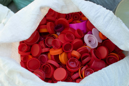 Colorful red plastic bottle caps background in cellophone package recycling eco friedly concept reuse for environmental protection, close up, copy space