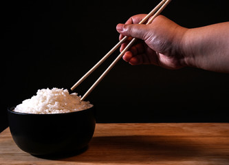 Rice in a bowl on a black background in the studio.
